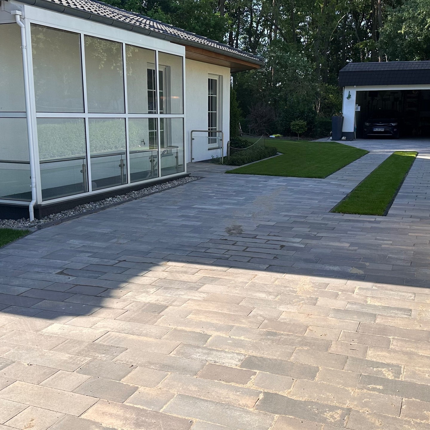 Aussenanlage mit Terrasse aus EMPEROR Keramikplatten, RINN Padio Pflaster, Rollrasen und RainBird Beregnung hergestellt.