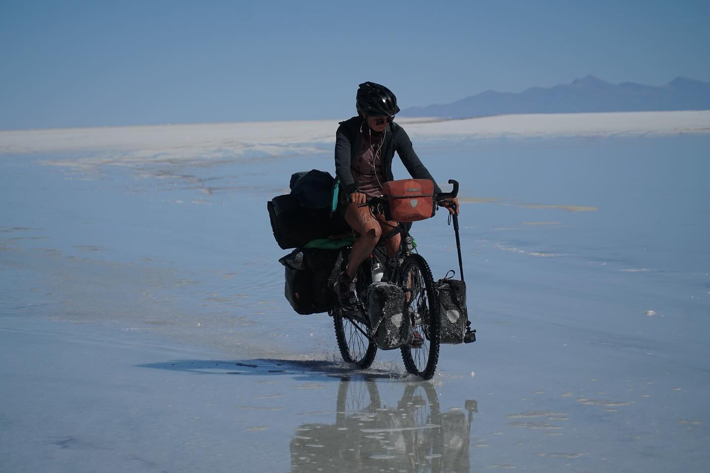 Die drei Tage ohne Fahrrad taten gut, doch wir freuten uns auch wieder weiter fahren zu können. Vorallem stand eines der absouluten Highlights an. Mit den Rädern auf den Salzsee. 1 ½ Tage nichts außer weiß. Keine Straßen, keine Menschenseele, nur wir mit unseren Fahrrädern. Man fährt km um km und man verliert jegliche Orientierung. Der Süden sieht genauso aus wie der Norden oder der Westen oder der Osten. Nur eine kleine Orientierung am Horizont und die Sonne. Der Vulkan Tunupa der aber am Fuß auch über 15 km Breite hat. Ohne Navi hätten wir den Ausgang also auch so nicht gefunden. Ein nichts aus weiß und trotzdem unbeschreiblich schön. Doch das Fahren an sich war mühsam. Da die Regenzeit gerade erst zu Ende gegangen ist, war das Salz noch sehr nass und es fühlte sich so an, als würde man über Kleber fahren. Dazu hatte man das Gefühl gar nicht vom Fleck kommt. Am Nachmittag hielten wir deshalb einfach an und schlugen mitten auf der weißen Ebene unser Zelt auf. Genossen noch den wunderschönene Sonnenuntergang und gingen relativ früh schlafen. Denn wir wollten uns unbedingt den Sternenhimmel anschauen. Die Erwartungen waren zwar schon hoch, doch was wir sahen übertraf alles, was man sich hätte vorstellen können. Ein Bild, das keine Kamera einfangen kann. Ein Bild das einfach nur unbeschreiblich ist.
Die restlichen 60 km legten wir dann am nächsten Vormittag auf dem Salar zurück. Zum Glück auch mit besseren Bodengegebenheiten, sodass wir nicht mehr nur noch das Gefühl hatten, am Boden zu kleben.
Doch der Salzsee hat auch Spuren hinterlassen. Nicht nur wir waren von oben bis unten voller Salz, auch unsere Taschen und Fahrräder waren komplett gesalzen. Das konnte natürlich unmöglich so bleiben, da dir Fahrräder sonst wahrscheinlich schon auf dem Weg nach La Paz völlig verrostet gewesen wären. Wir verbrachten also den ganzen Nachmittag damit, unsere Fahrräder in der Wasserquelle vom Vulkan (die einzige Wasserquelle, die nicht salzig war) sauber zu machen.